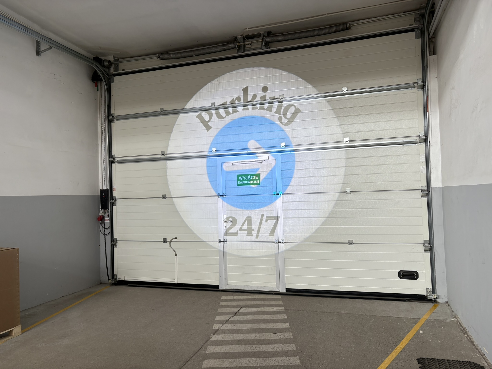 brama garażowa, na niej duża projekcja led parking 24/7